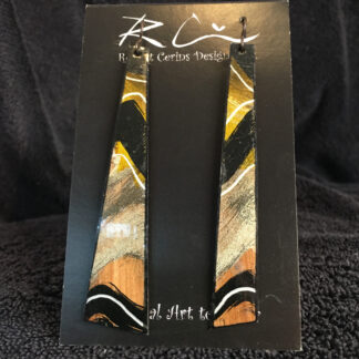 the image in this photo is of a pair of handmade and hand painted earrings. The colours are black, gold, bronze, and white. The ear wires are hypoallergenic Niobium and the wearer is guaranteed a soothing earring wearing experience or their money back.